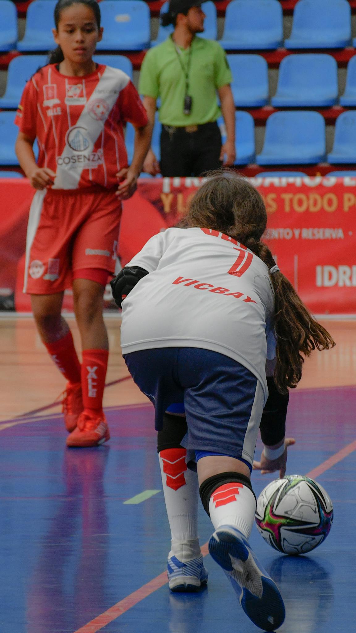 Girls competing in an indoor soccer game focused on teamwork and skills.