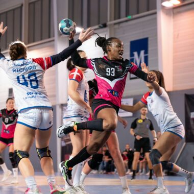 A thrilling moment in a women's indoor handball match capturing the excitement of the game.
