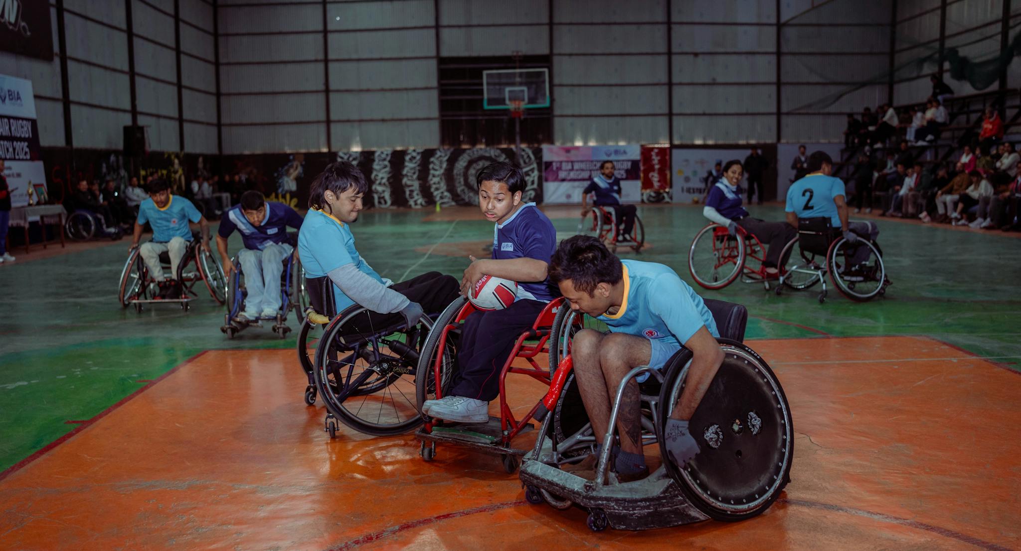 Intense wheelchair rugby match highlighting teamwork and sportsmanship indoors.